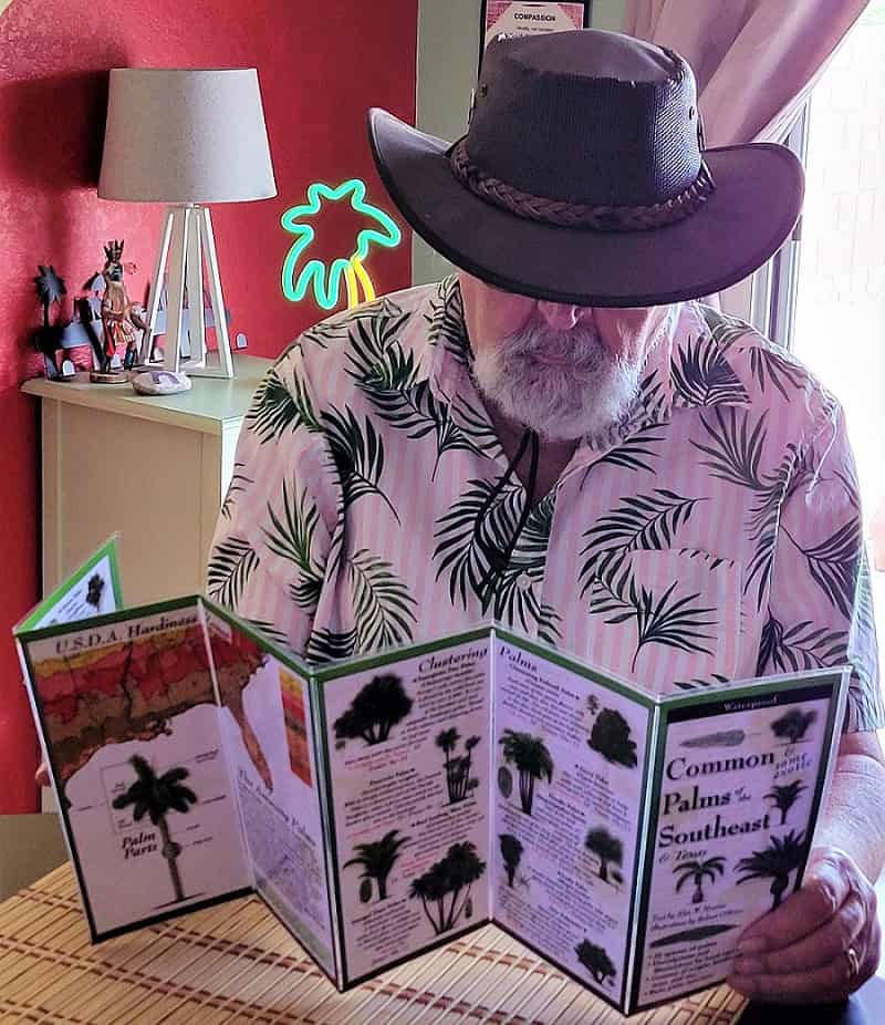 Man looking over a guide to southeastern palm trees