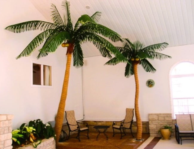 two artificial palm trees in the room of a home two artificial palm trees in the room of a home