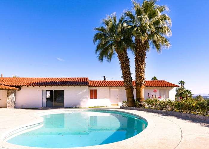 Backyard of a Home with 2 palm trees near the pool