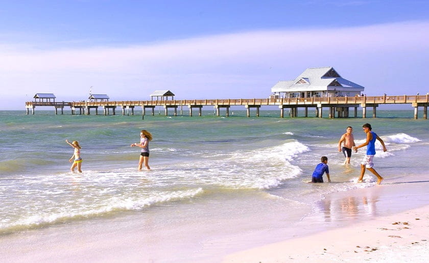 kids play in the calm waves at Clearwater Beach with pier in the background kids play in the calm waves at Clearwater Beach with pier in the background