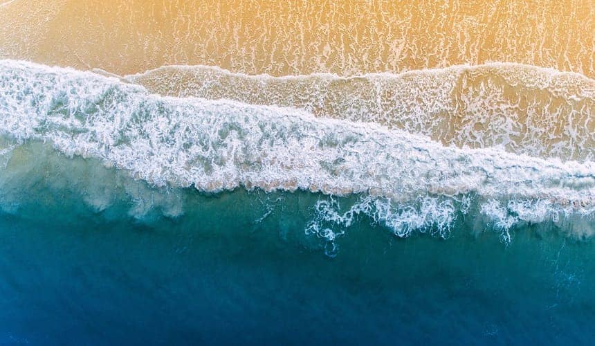 Aerial view of waves breaking on beach sand Aerial view of waves breaking on beach sand