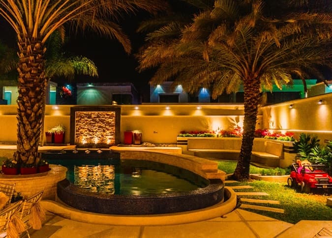 pool-side architecture with lit palms at night